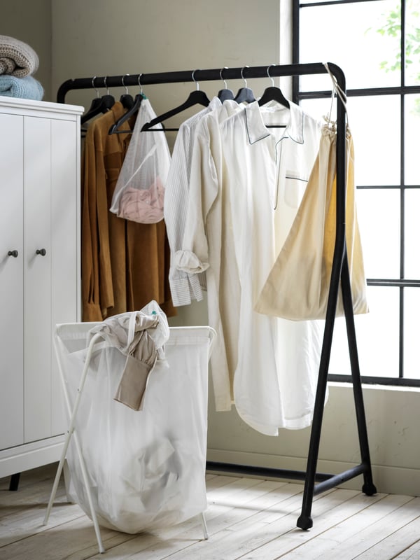 Coin dressing avec porte-manteau noir, sac de linge et armoire blanche