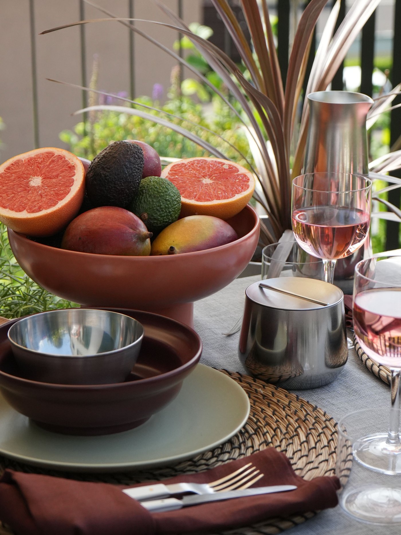 Gedeckter Tisch im Freien mit Früchten, Roséwein. IKEA BLANDA BLANK Edelstahlschale, braune Schale.