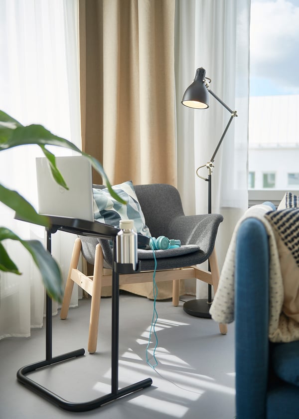Mysig hörna i vardagsrummet med fåtölj och laptopstöd