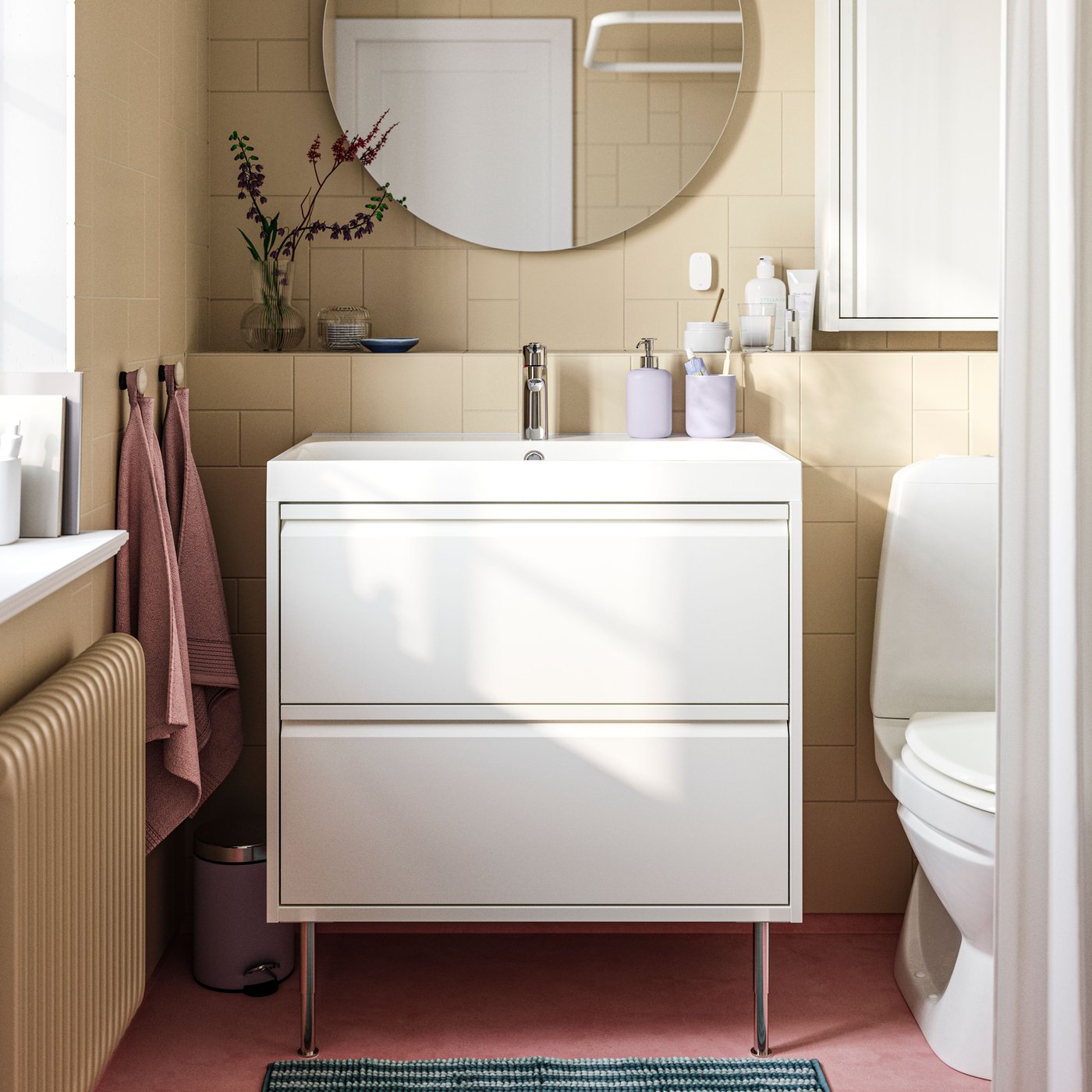 A white ÄNGSJÖN wash-stand with two drawers and legs is mounted in a bathroom with light brown tiles below a FAXÄLVEN mirror.