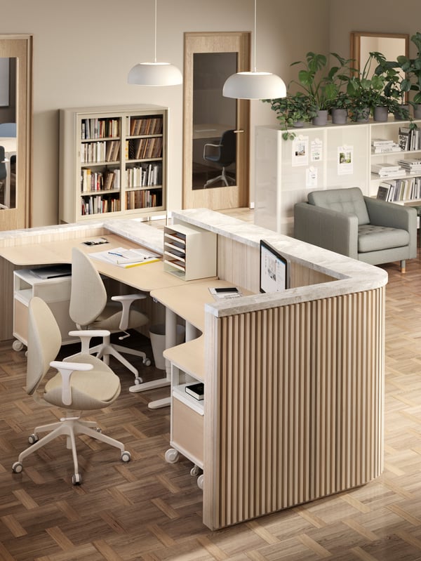 A reception desk made from two BEKANT desks with two HATTEFJÄLL chairs, and two BEKANT storage units on castors beneath.