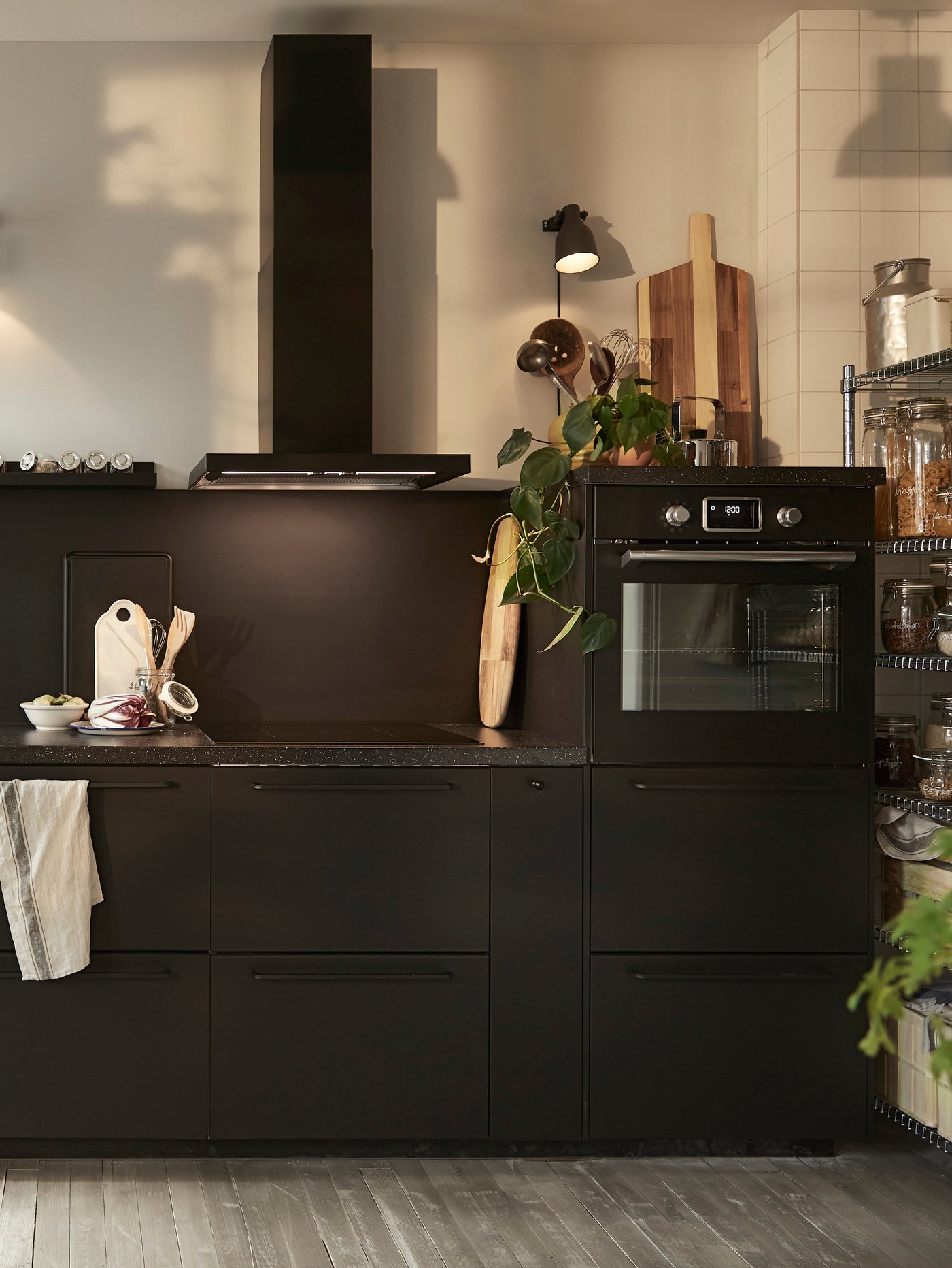 A black METOD kitchen with black cabinets and a black work top and an acacia SMÅÄTA chopping board.