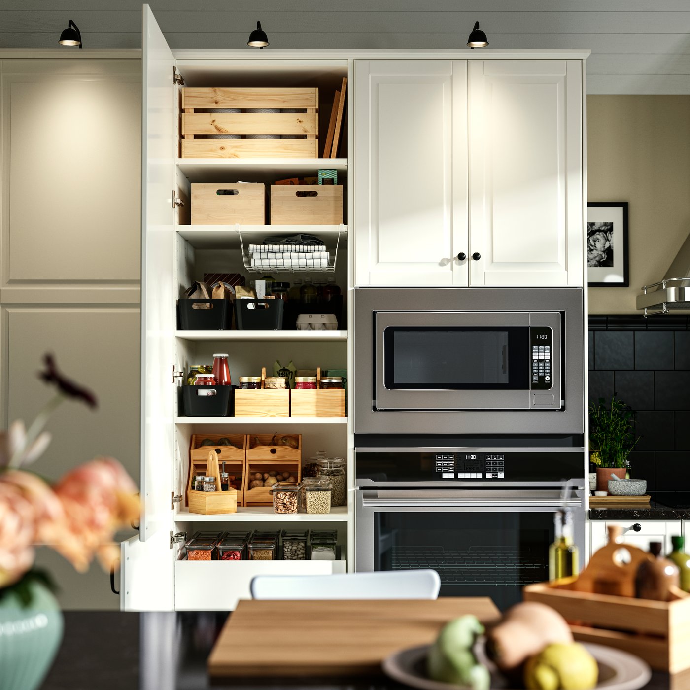 Una cocina moderna con un horno y un microondas de acero inoxidable, además de un gabinete cuidadosamente organizado con cajas de almacenamiento UPPDATERA.