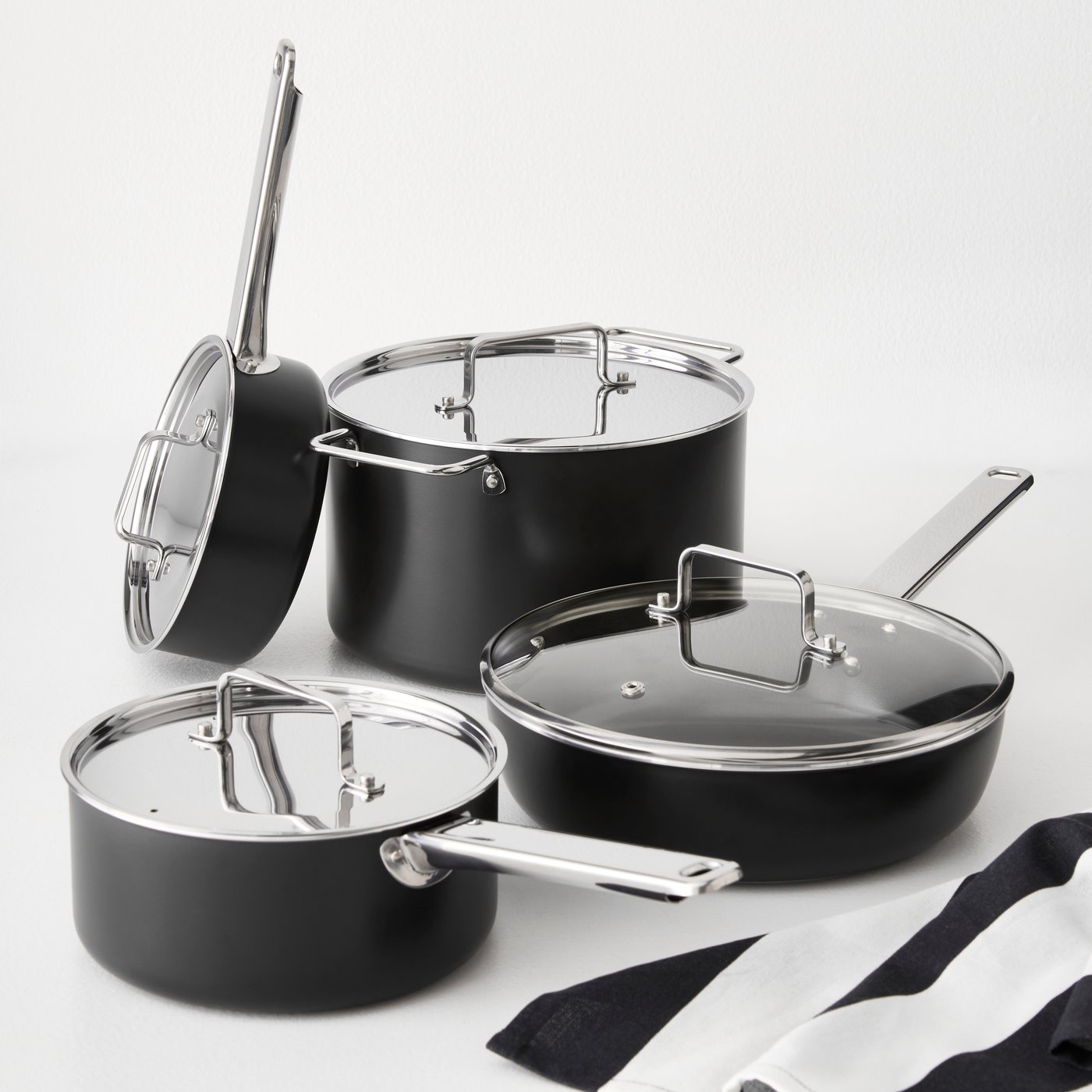 A white countertop with a black-grey GULDÖRING 8-piece cookware set, featuring non-stick stainless steel pots and a sauté pan