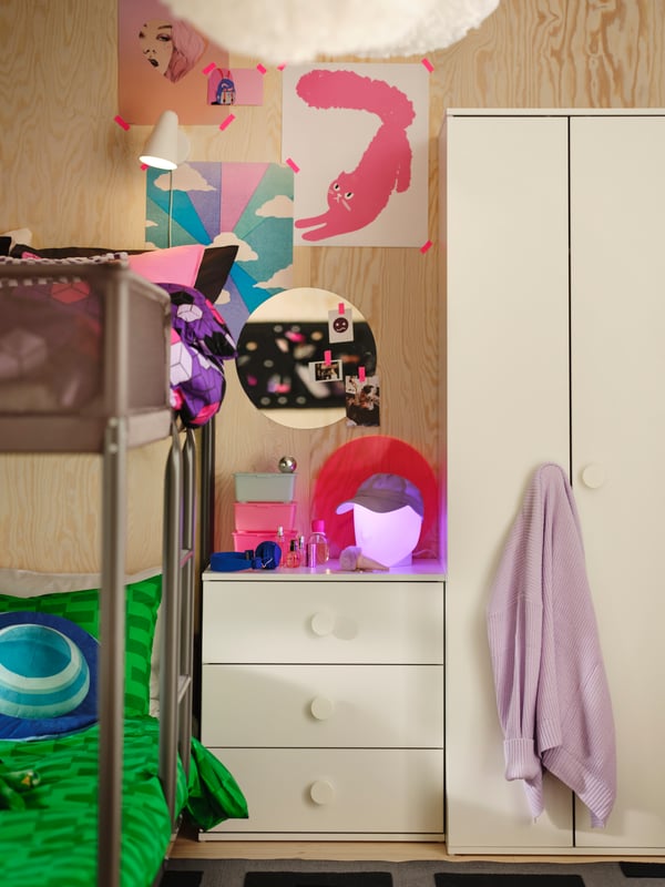 Accanto a un letto a castello TUFFING ci sono un guardaroba GODISHUS e una cassettiera con uno specchio e dei disegni rosa acceso.