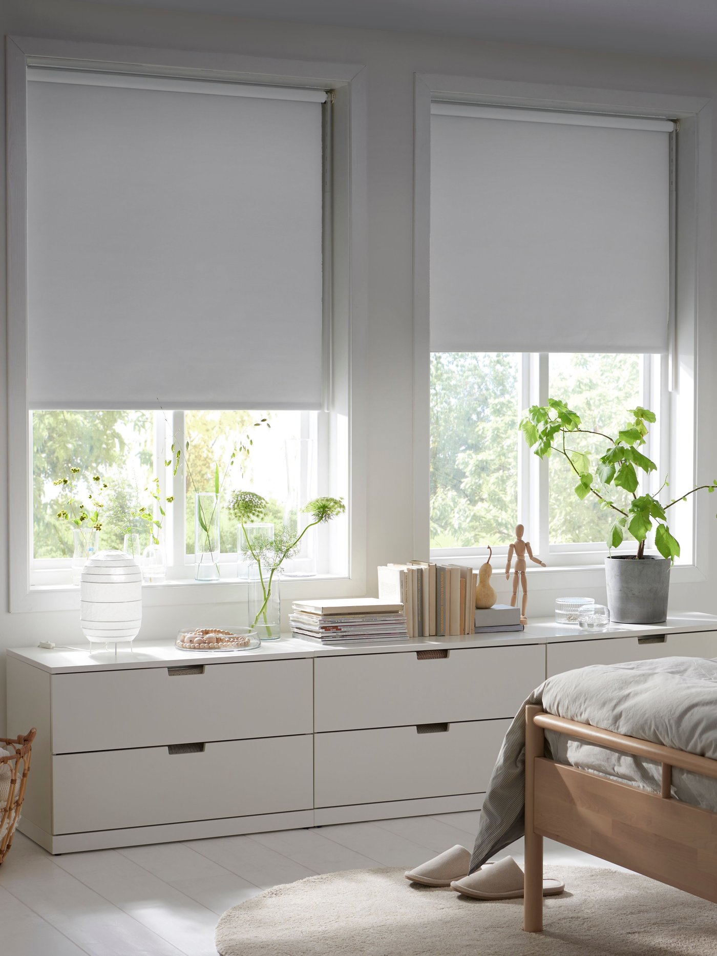 A white FRIDANS block-out roller blind in the bedroom