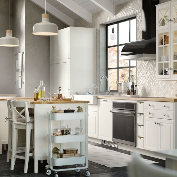 A bright kitchen has BODBYN fronts in off-white and a kitchen island with two chairs and two big pendant lamps above it.