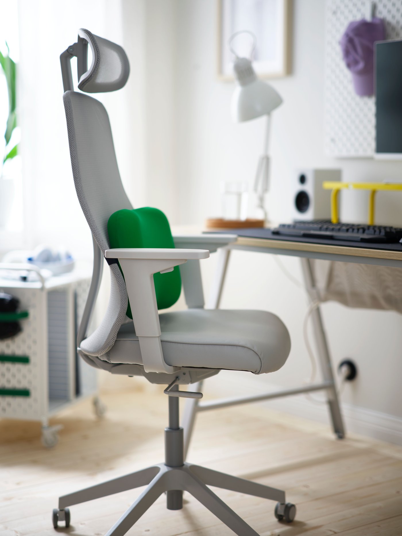 A memory foam, green LÅNESPELARE lumbar cushion is buckled onto the mesh backrest of a light grey MATCHSPEL gaming chair.