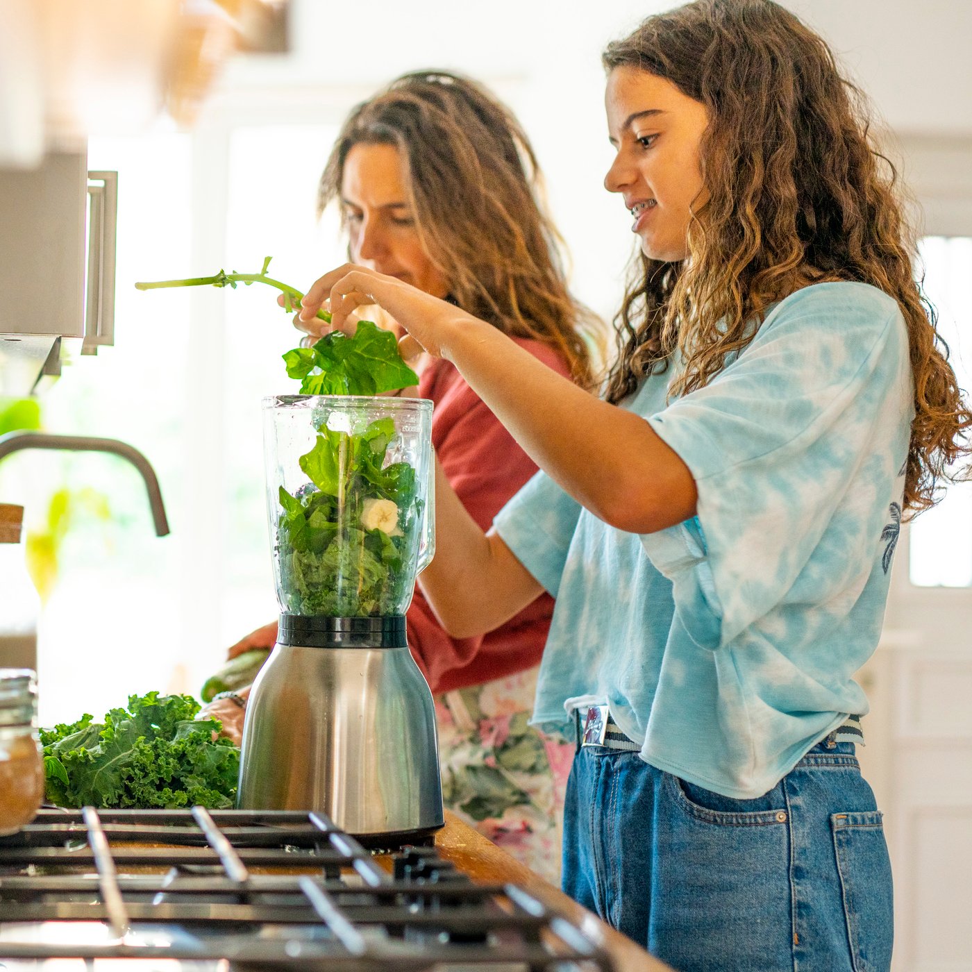 Two people making green smoothies in a kitchen