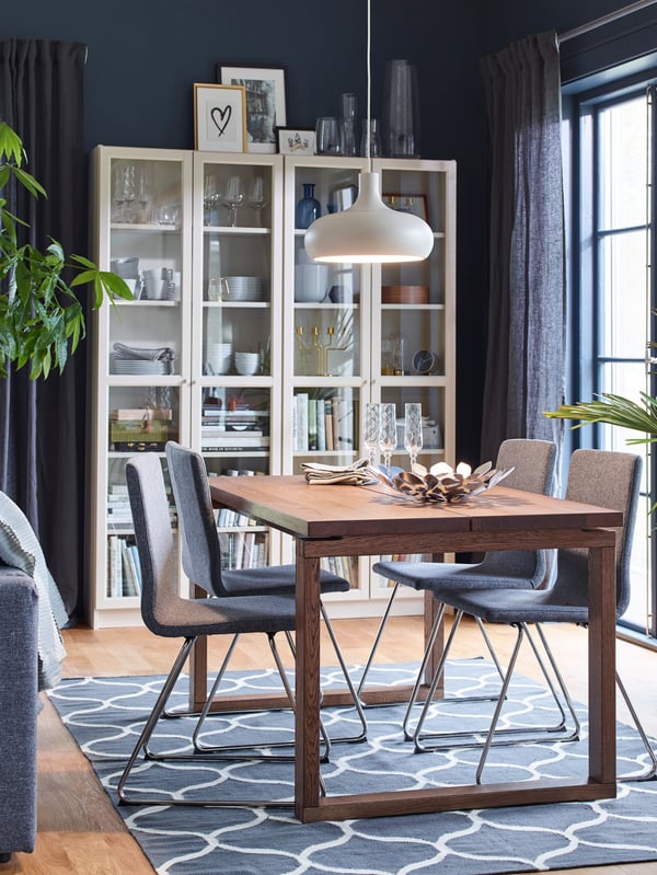 A beige BILLY bookcase with glass-doors in the dining room