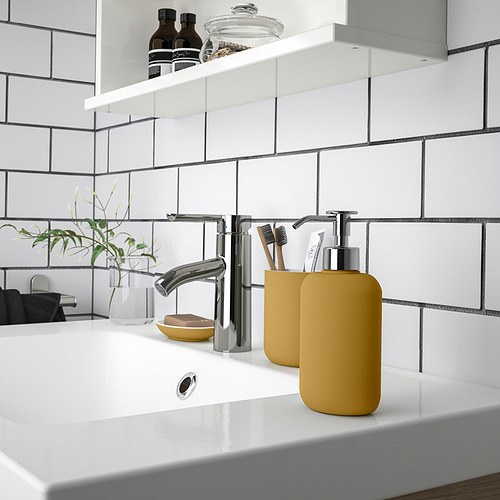 A dark yellow EKOLN soap dispenser in the bathroom