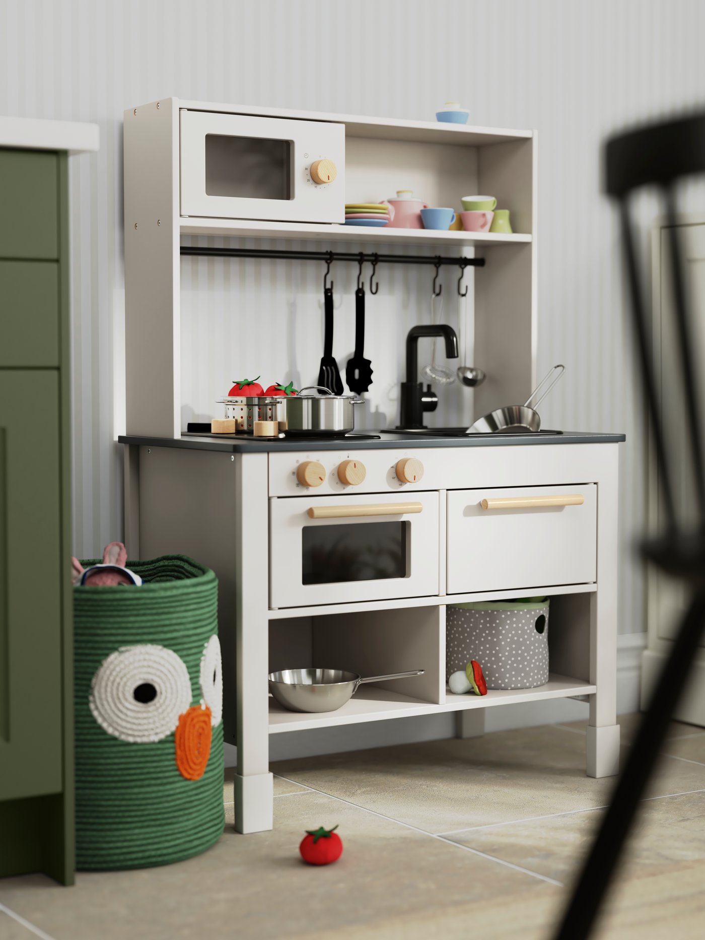 A SILLTRUT kitchen for children in a soft grey has pans and pots and other play kitchen utensils stacked on top of it.