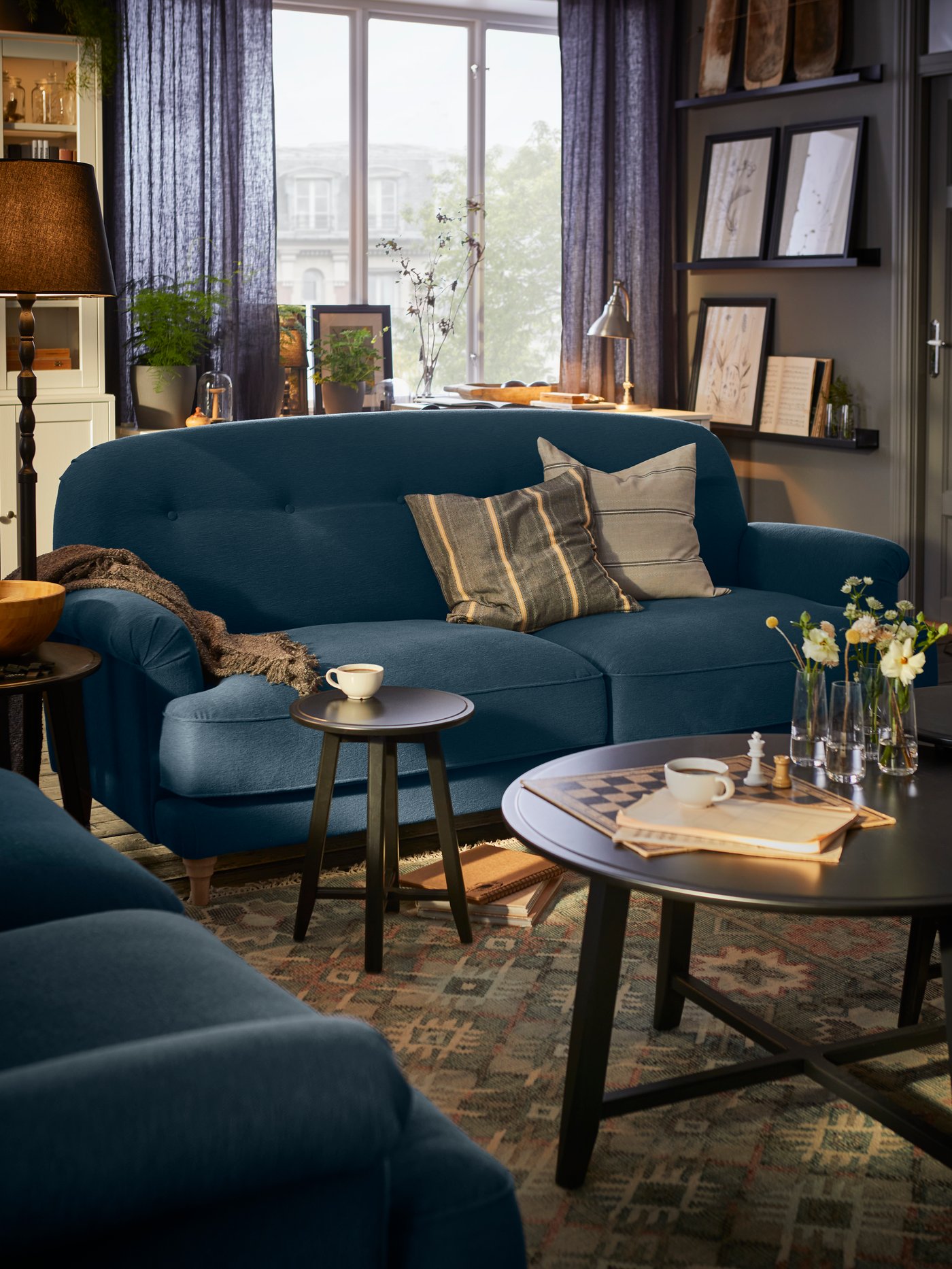 Dans un salon de style campagne, deux canapés ESSEBODA bleus sur un tapis tissé à plat VESTERVIG et deux tables KRAGSTA.
