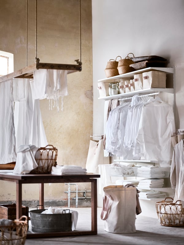 A laundry room with a brown wooden table in the centre and a BOAXEL system mounted on the white wall.