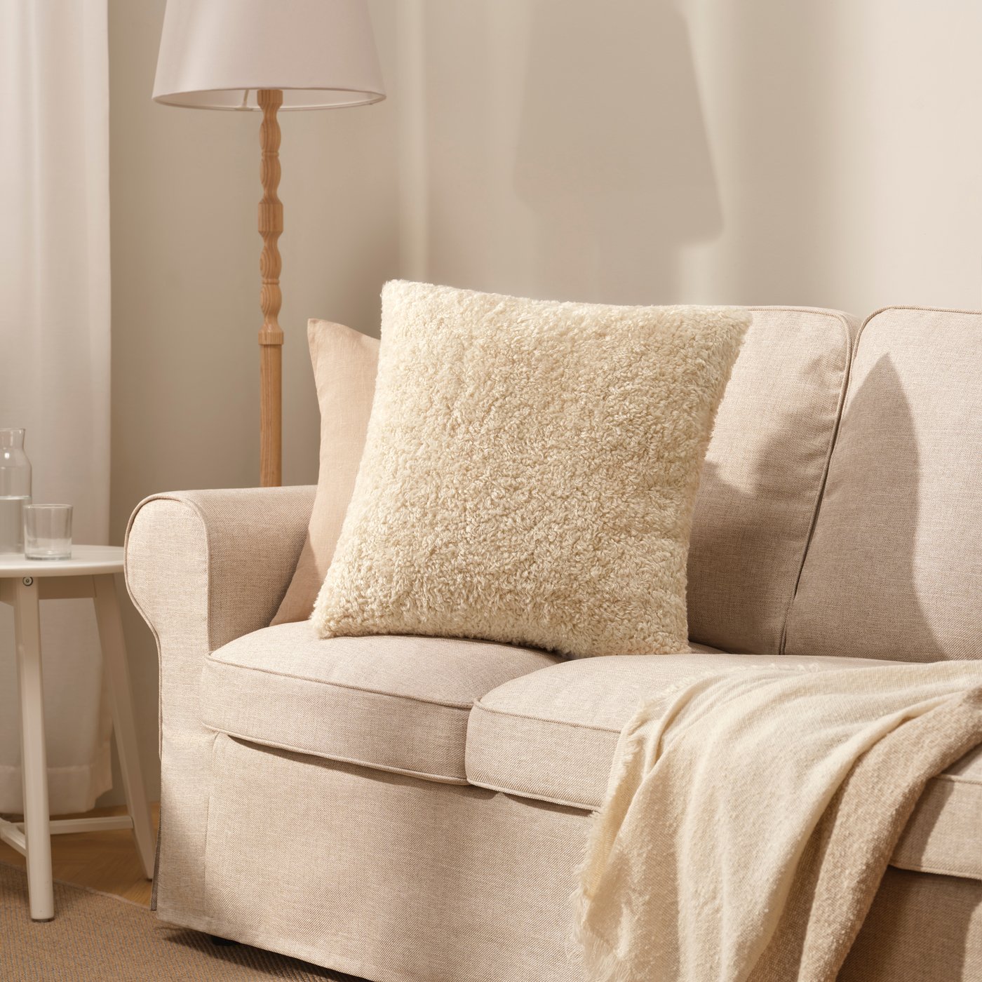 An off-white ÅSJORDFLY cushion cover in the living room