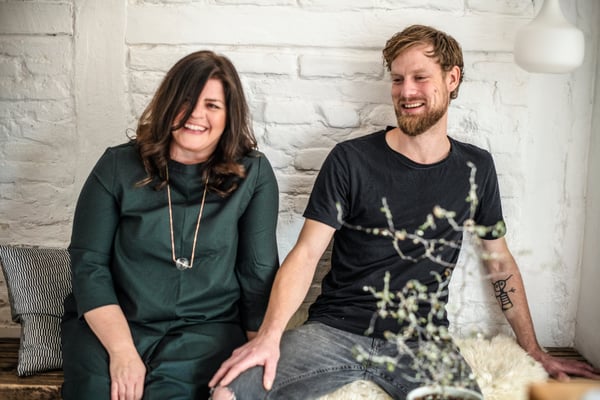 A young couple sitting on a couch laughing.
