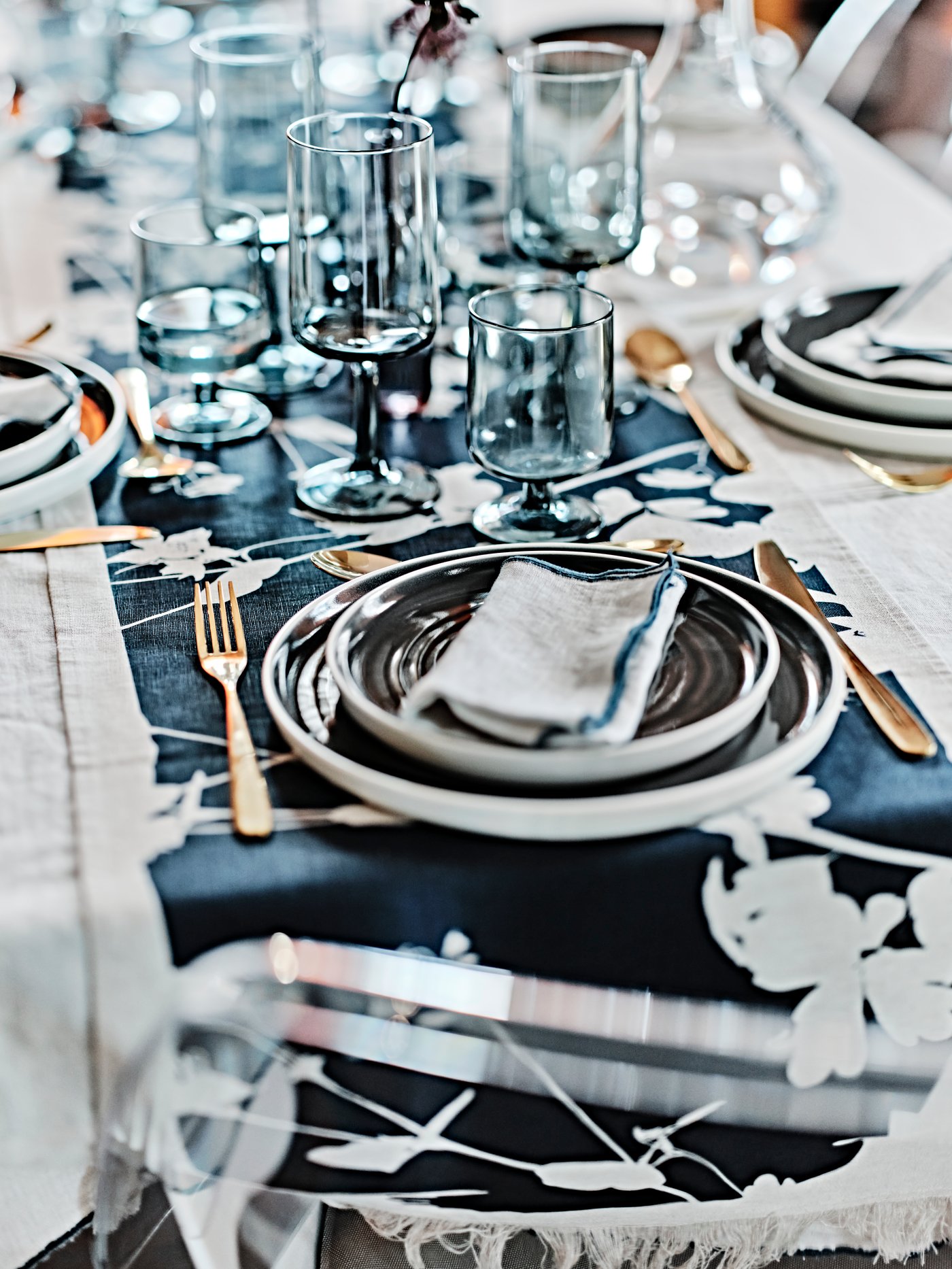 A small wedding table is set with dark and like blue dinnerware with flowers placed as a centre piece.  