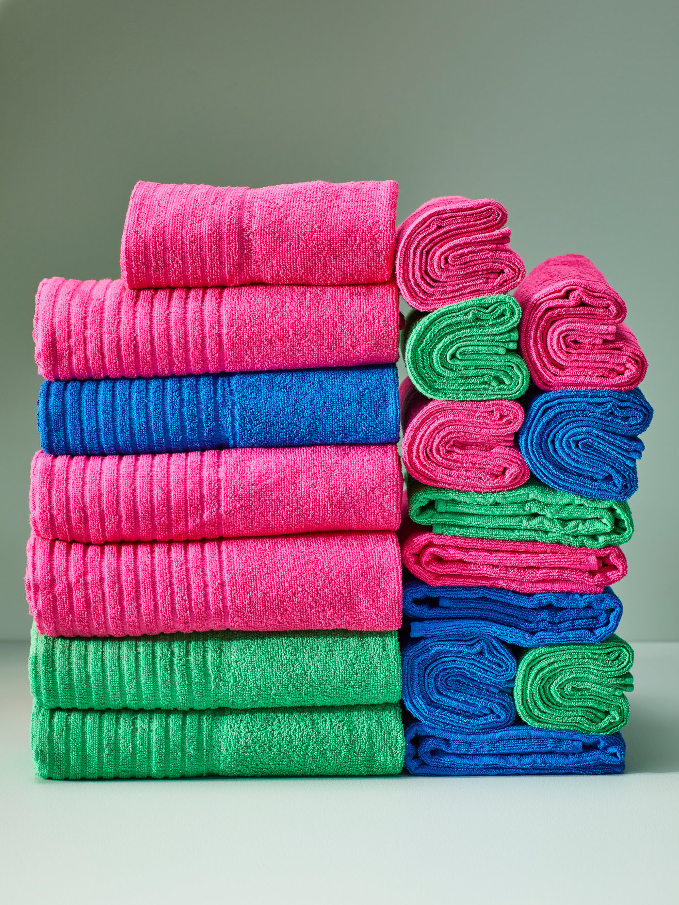 Une collection de serviettes colorées empilées sur un fond vert.