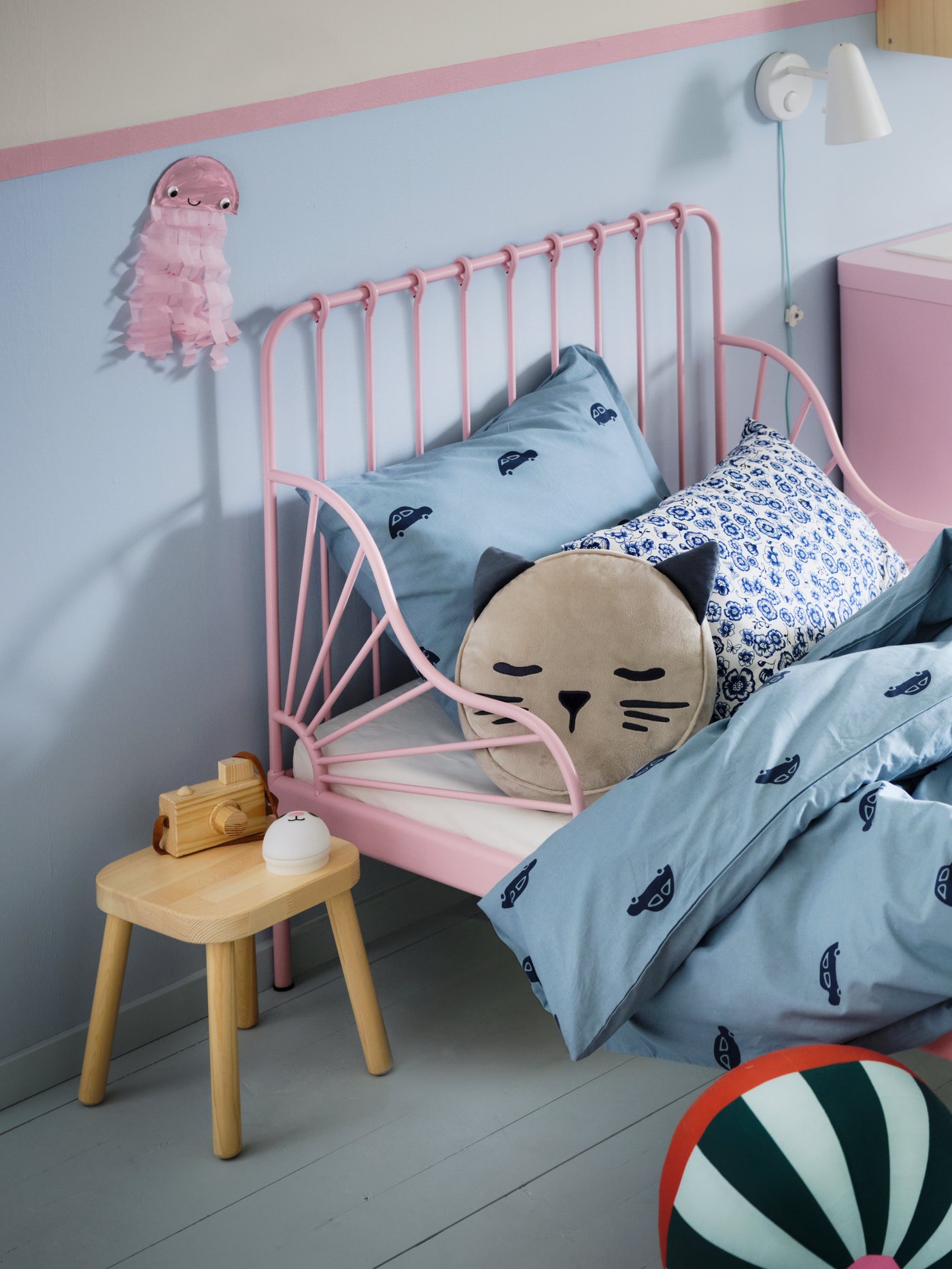 Una cama infantil FLISAT rosada con dos cojines encima.
