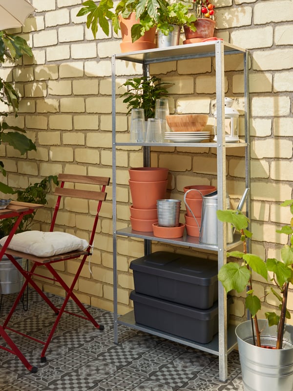 Una estantería con cuatro estantes para guardar cajas, maceteros, platos y vasos al alcance de la mesa.
