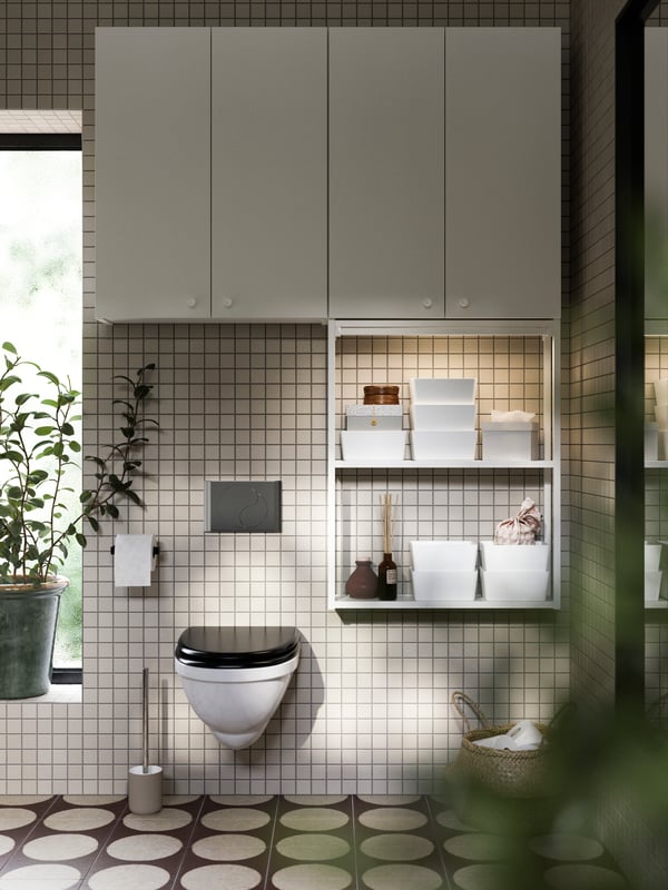A bathroom with an ENHET wall frame with shelves in white, storage with ENHET doors in white and EKOLN toilet brush in beige.