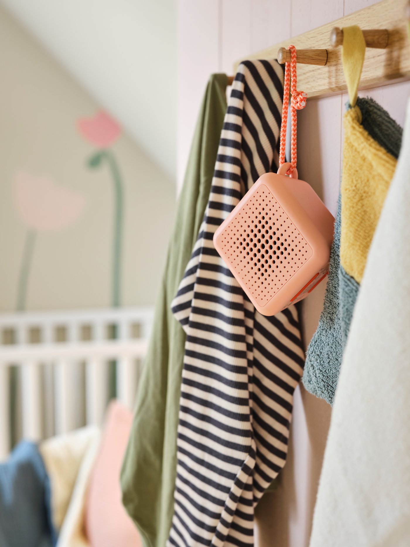 A waterproof pink VAPPEBY speaker hangs on an oak HÖVOLM rack with 6 knobs alongside a wash mit and clothing.