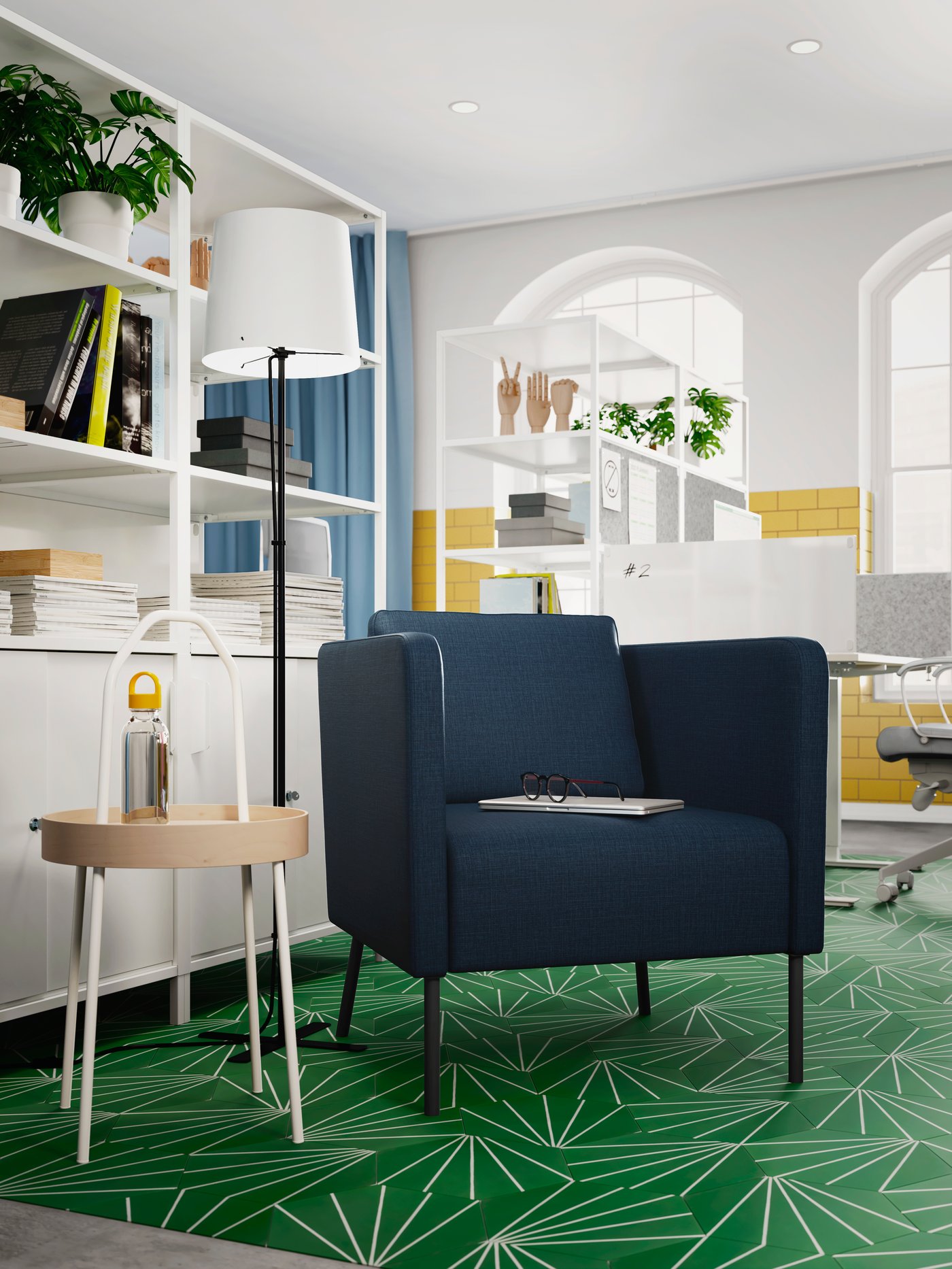 A green-floored, airy office with a dark-blue EKERÖ armchair standing next to a BURVIK side table and white cabinets.