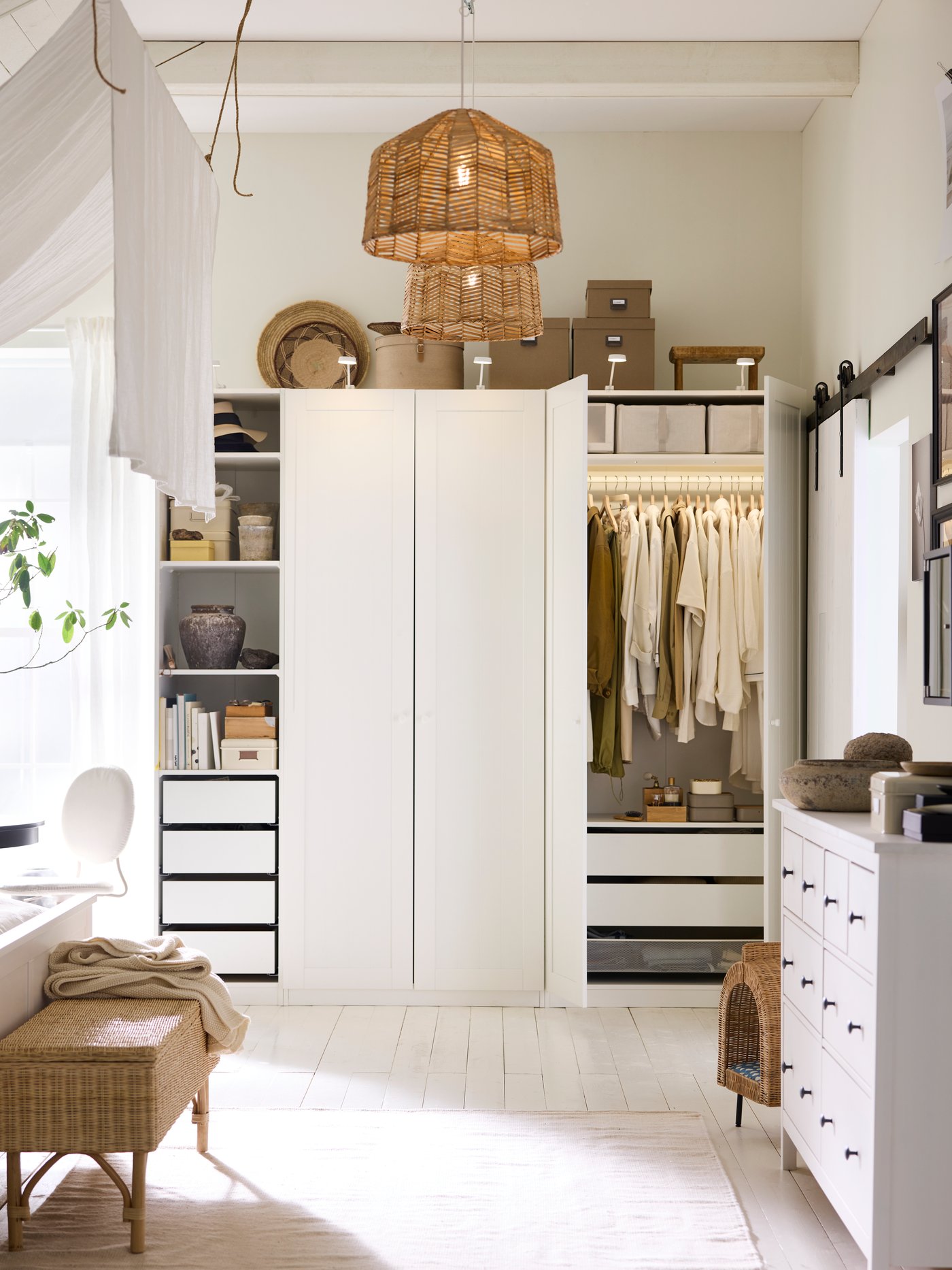 A white PAX/GULLABERG wardrobe combination in a white bedroom with two doors open and a TOLKNING bench with storage in front.