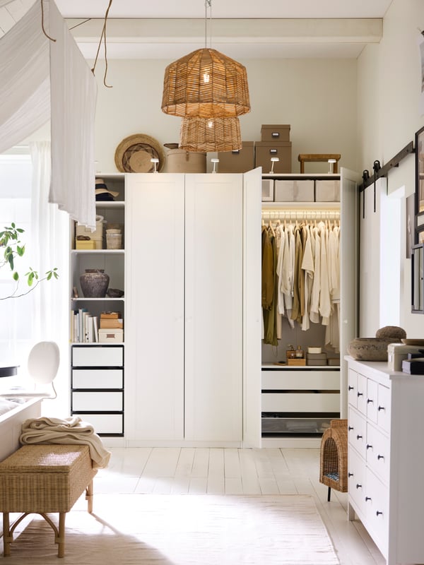 A white PAX/GULLABERG wardrobe combination in a white bedroom with two doors open and a TOLKNING bench with storage in front.