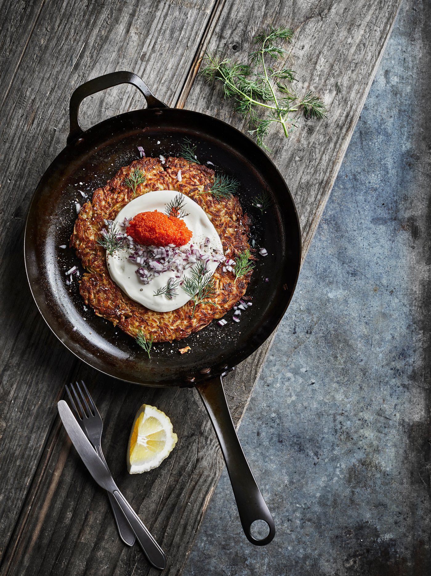 En stekpanna på ett bord med rösti och topping.