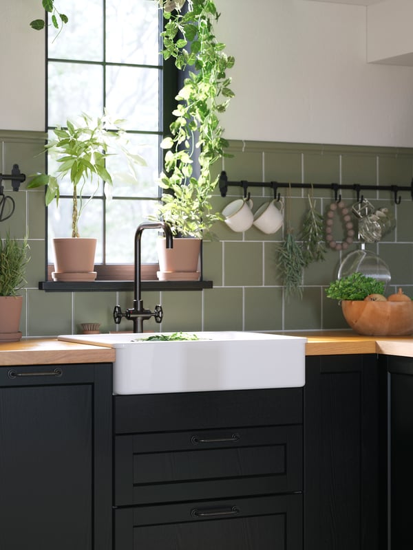 A white HAVSEN sink bowl with a visible front and a black kitchen mixer tap are seen in a LERHYTTAN black-stained kitchen.