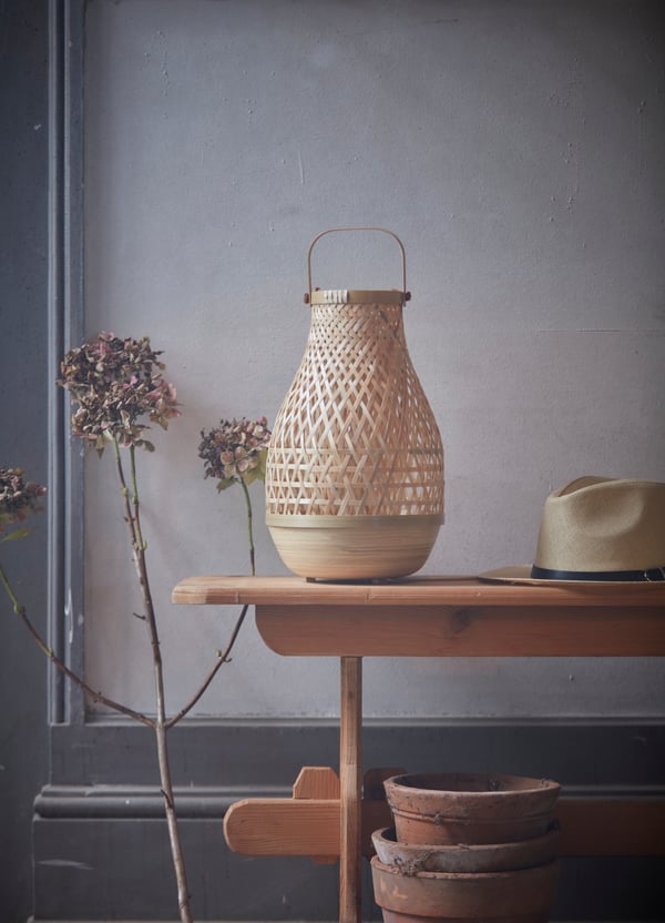 A small MISTERHULT lamp sits on a wooden bench in a light toned room with a rustic vibe