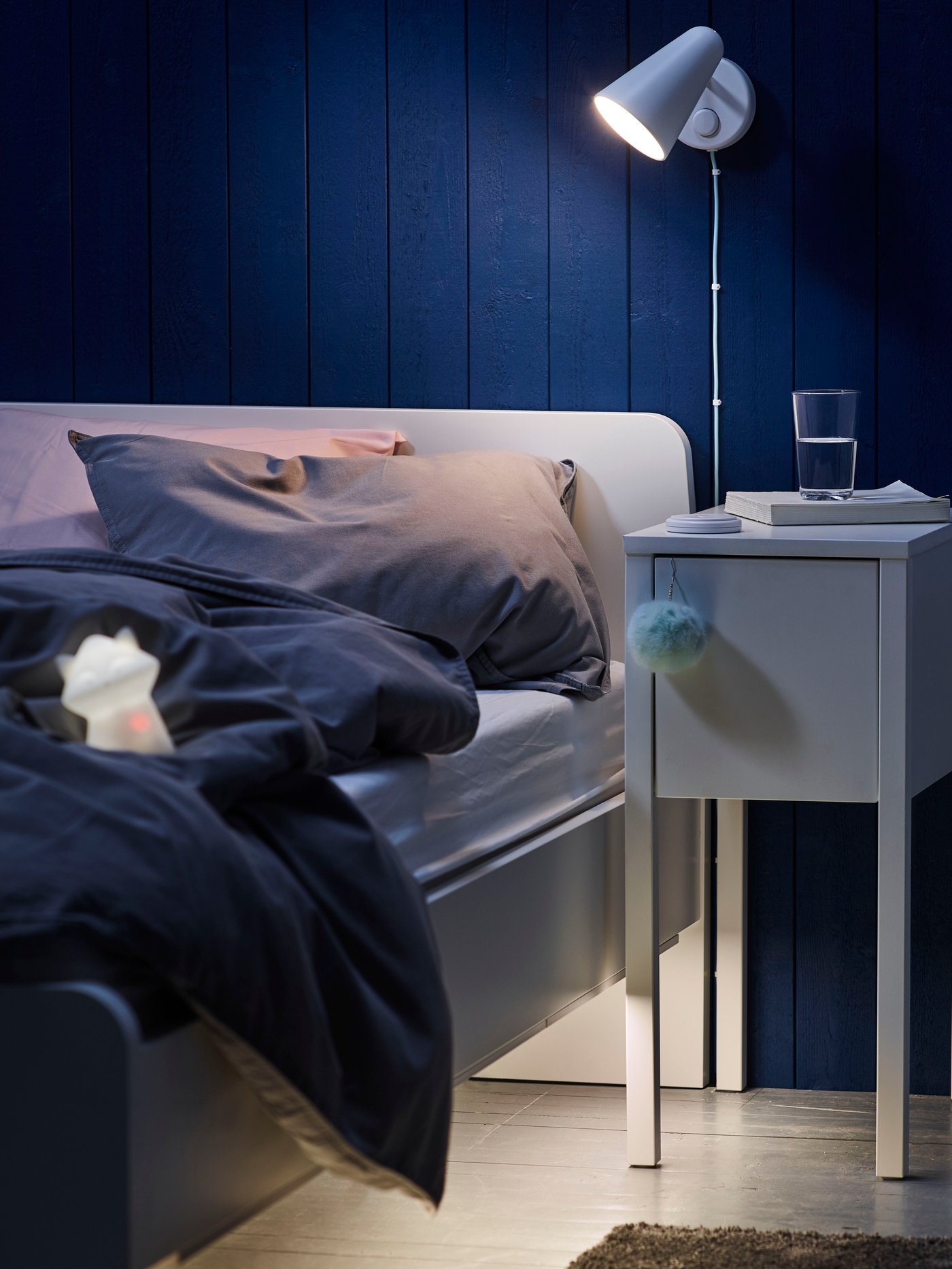 A bedroom with grey walls containing a bed with a BJÖRKSNÄS bed frame in birch, a bedside table in birch and white bed linen.