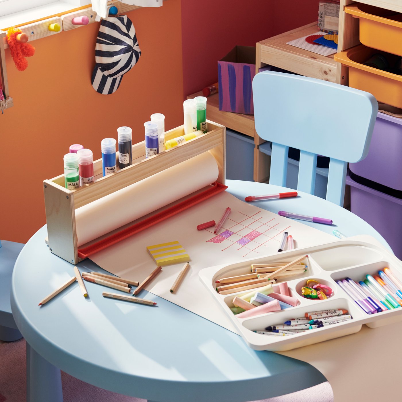 Two children’s chairs and a children’s table from the MAMMUT series in light blue. Art materials are laid out on the table.