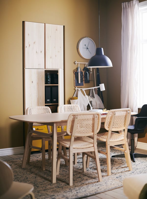 Mesa de comedor VOXLÖV rectángular con cuatro sillas rústicas. El comedor está sobre una alfombra MELHOLT de IKEA.