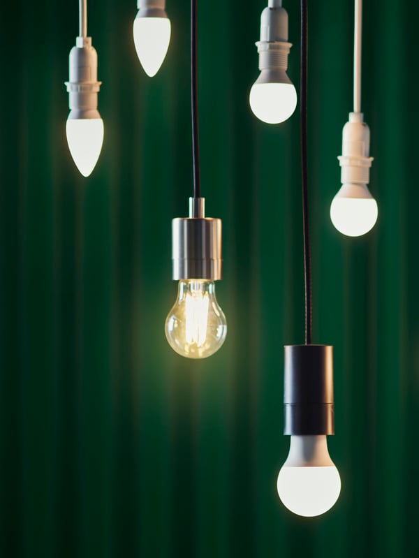 Plusieurs sources lumineuses SOLHETTA différentes sont suspendues au plafond. Le mur derrière est vert foncé. 