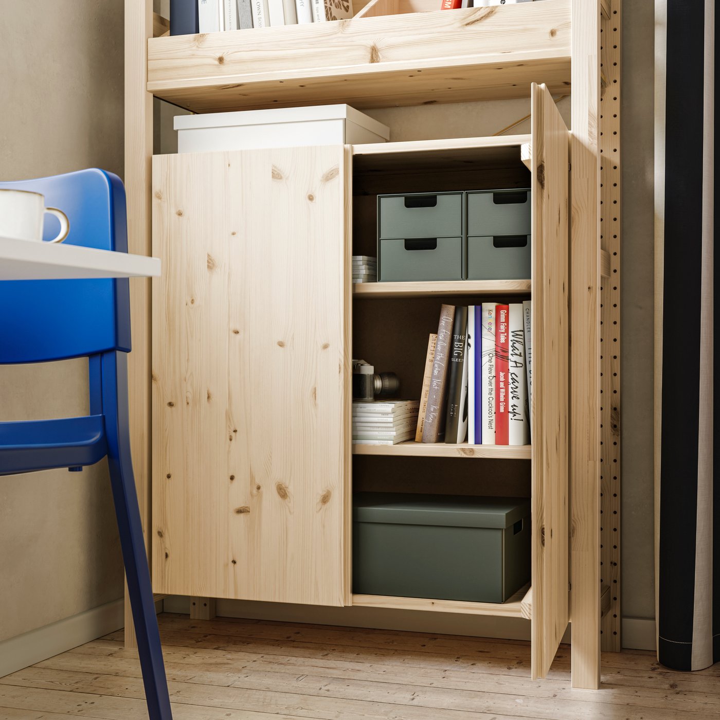 A light-filled space with an IVAR storage unit, where one pine cabinet door is left open to reveal neatly arranged books and storage boxes.