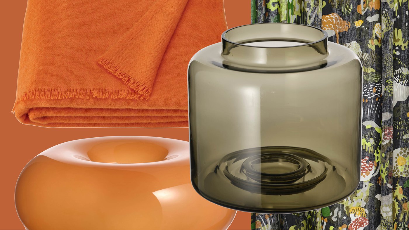 Un mélange d'éléments décoratifs colorés, notamment un plaid orange, un bol sculptural et un vase en verre fumé, reflète l'esthétique rétro souvent présente dans les collections IKEA.