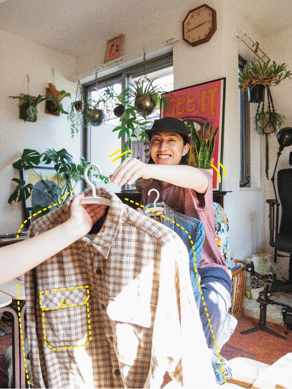 A person handing another person a hanger with a shirt on it.