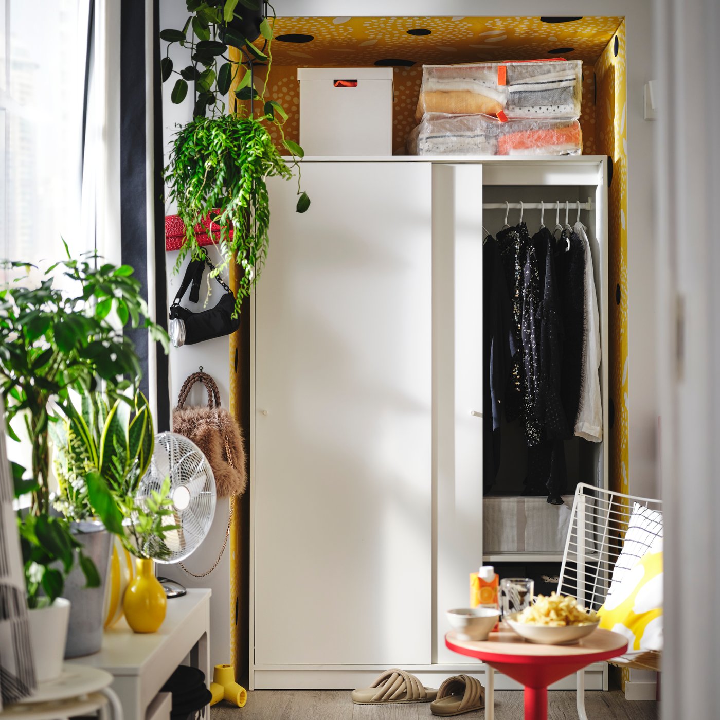 A white KLEPPSTAD wardrobe with sliding doors is open, showing neatly organised hanging clothes and storage boxes.