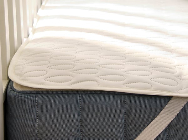A corner of a firm/light blue VALEVÅG pocket sprung mattress covered in a SOTNÄTFJÄRIL waterproof mattress protector.