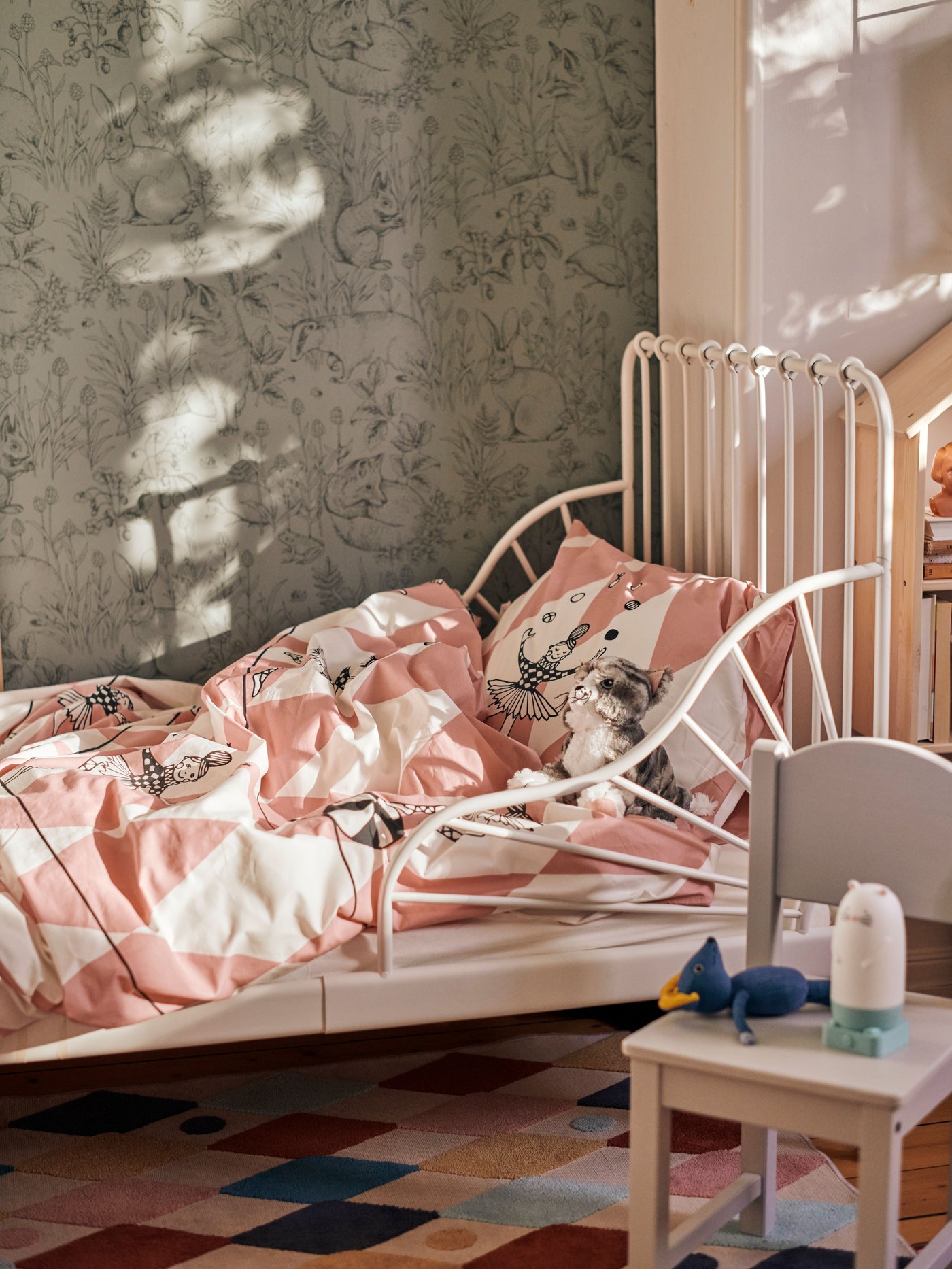 Una cama extensible de la serie SUNDVIK con ropa de cama infantil en tonos blancos y rosas