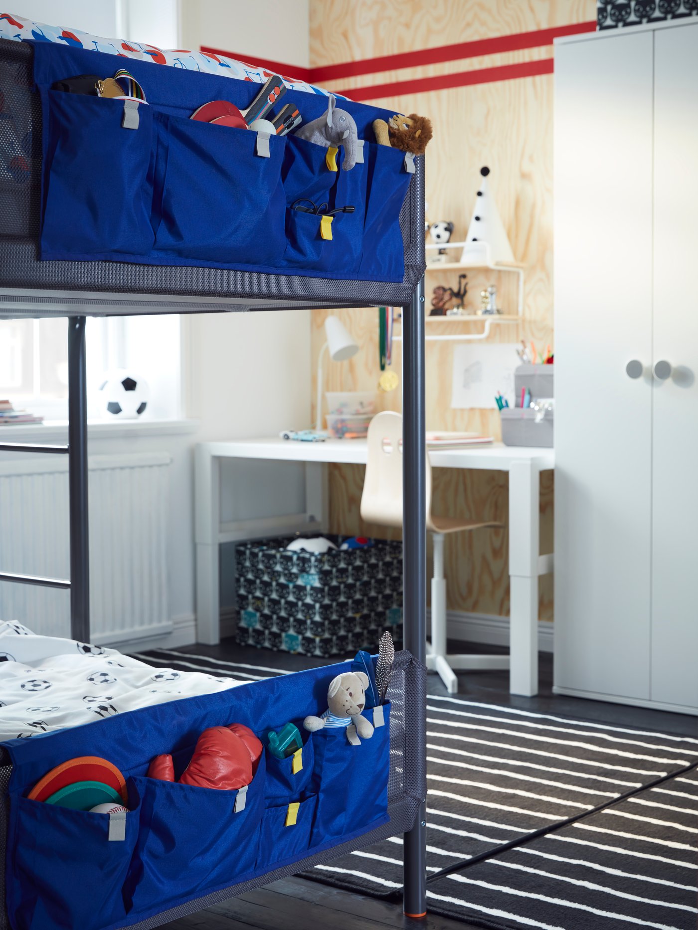 The bottom end of a grey TUFFING bunk bed with a deep blue pocket on each bed filled with toys, games and furry animals.
