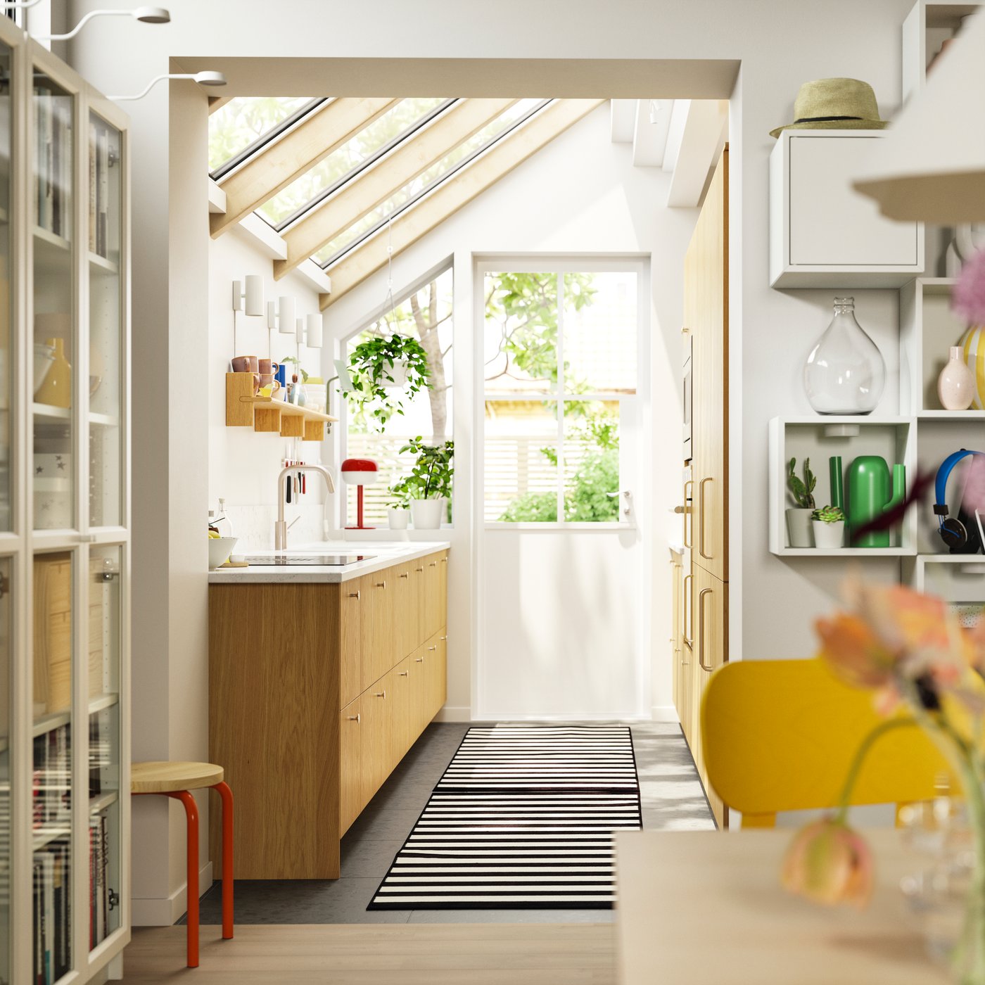 A bright kitchen with a slanted ceiling with windows and a door that faces the backyard has SINARP fronts in oak veneer.