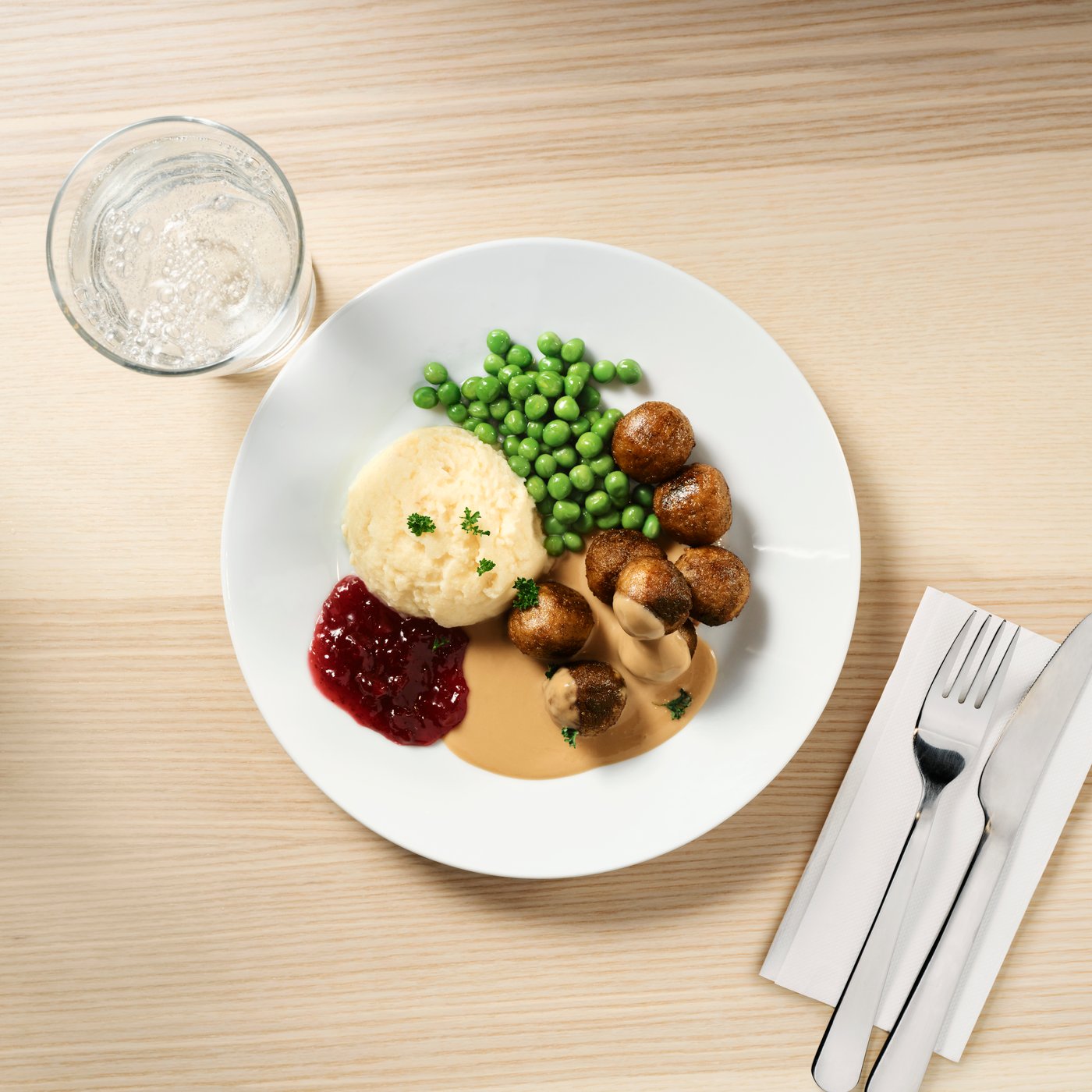 A plate of HUVUDROLL plant balls with peas, mashed potatoes and lingonberry jam