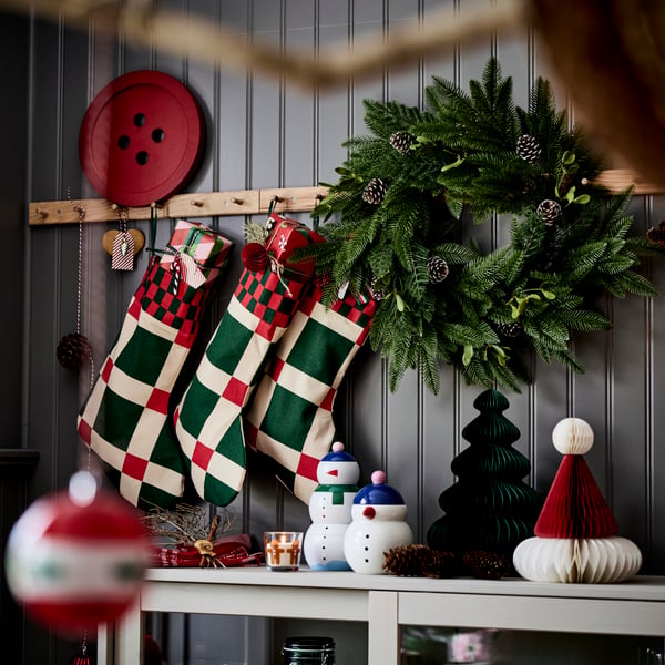 Three VINTERFINT Christmas stockings are hanging on racks with knobs above a sideboard.