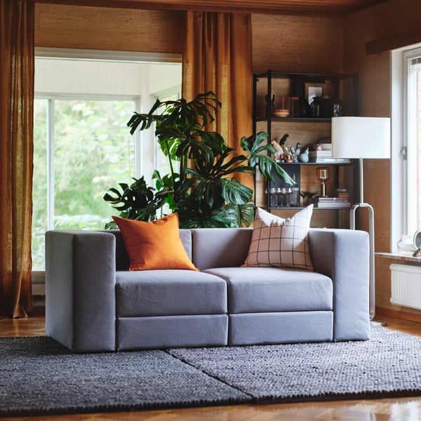 A grey JÄTTEBO 2-seat sofa with assorted cushions.