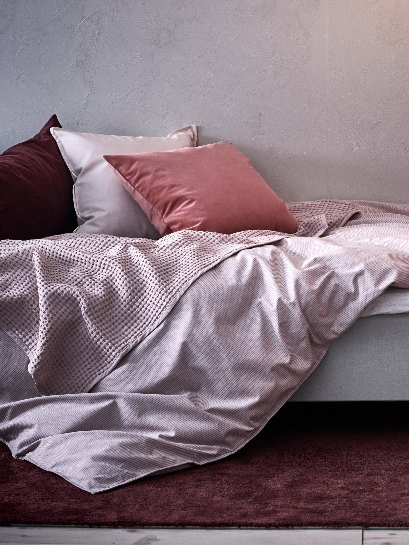Eine hellrosa VÅRELD-Tagesdecke im Schlafzimmer