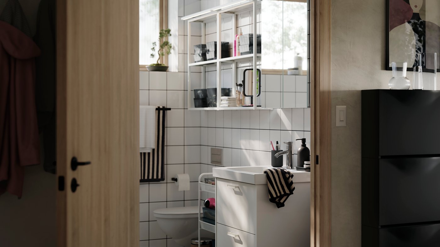 A bright and modern bathroom with white HAVBÄCK storage, white open ENHET shelves on the wall and striped soft towels.