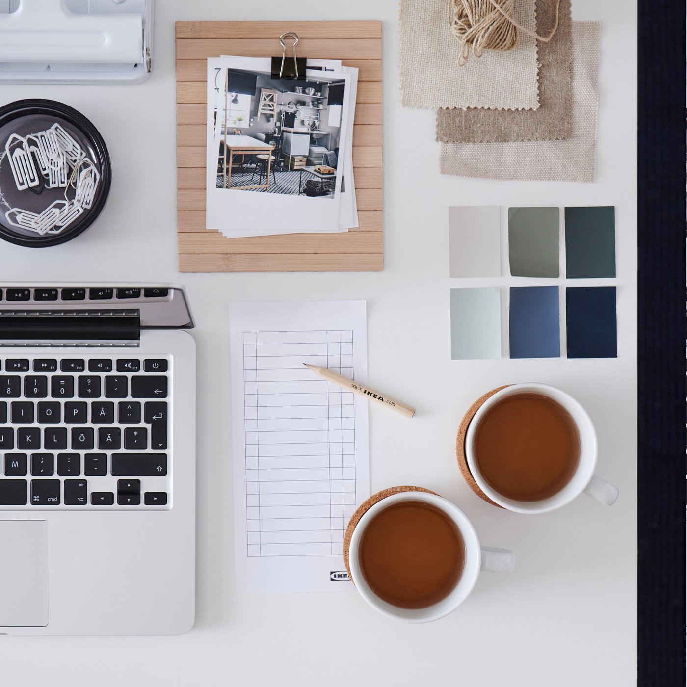 A white desktop with scattered but symmetrically arranged office accessories and desk-work paraphernalia.